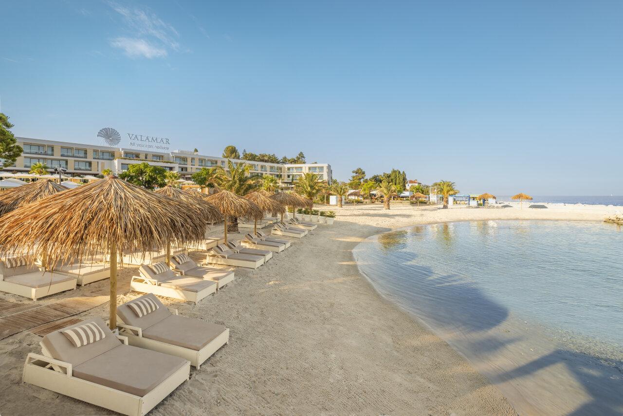 Val Marea Sandy Family beach in Poreč, featuring loungers under straw umbrellas along a sandy shoreline.
