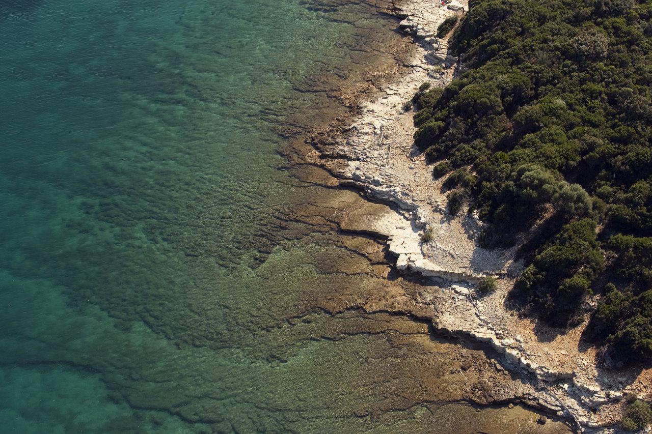 Aerial view of Brijuni National Park, showcasing crystal-clear waters, rocky shores, and lush greenery.