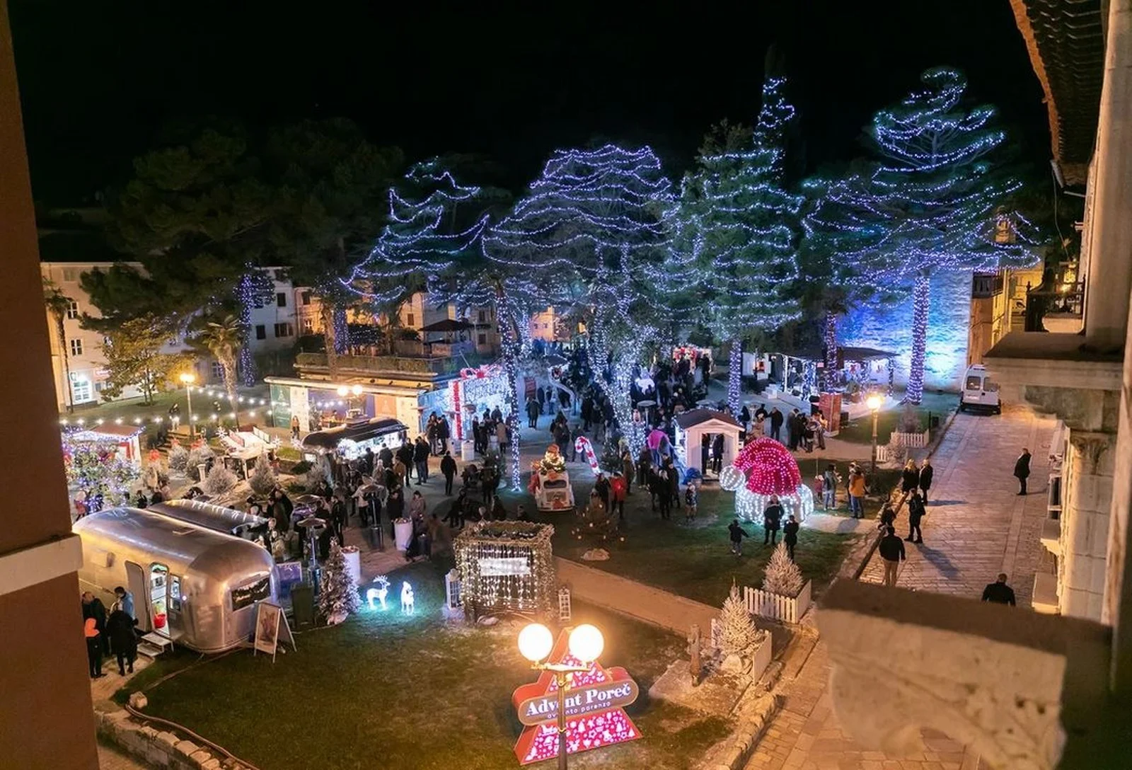 Weihnachtsmarkt in Poreč bei Nacht mit Lichterb&auml;umen und einladenden Essensst&auml;nden in Istrien, Kroatien. 