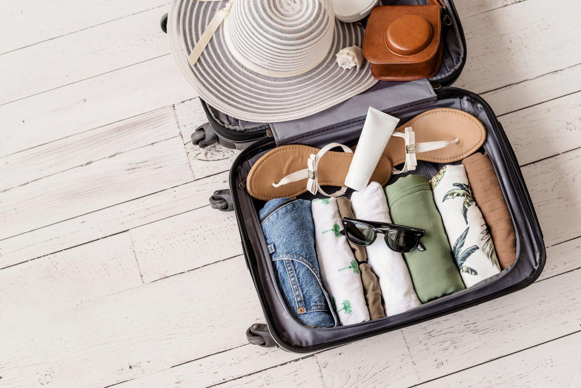 luggageandsuitcasepackingforvacationonwhitewoodenbackground