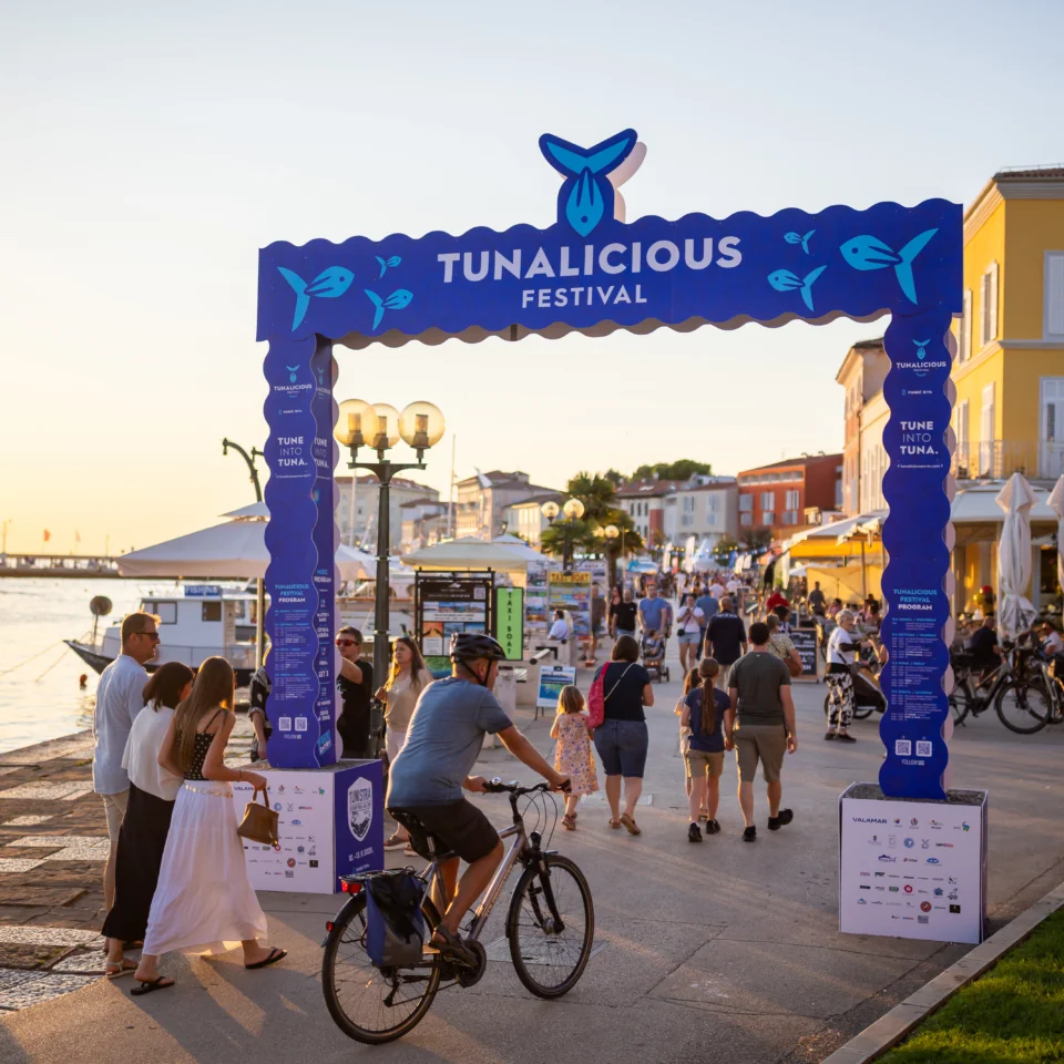 Tunalicious Festival entrance on the Poreč riva at sunset, with visitors walking along the promenade.