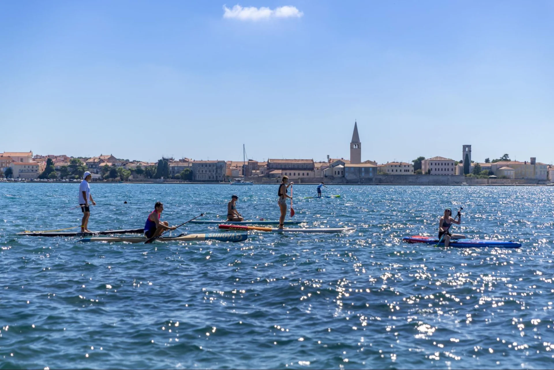 Stand-up paddleboarders taking part in a water sports event off the coast of Poreč, with the Old Town in the background.
