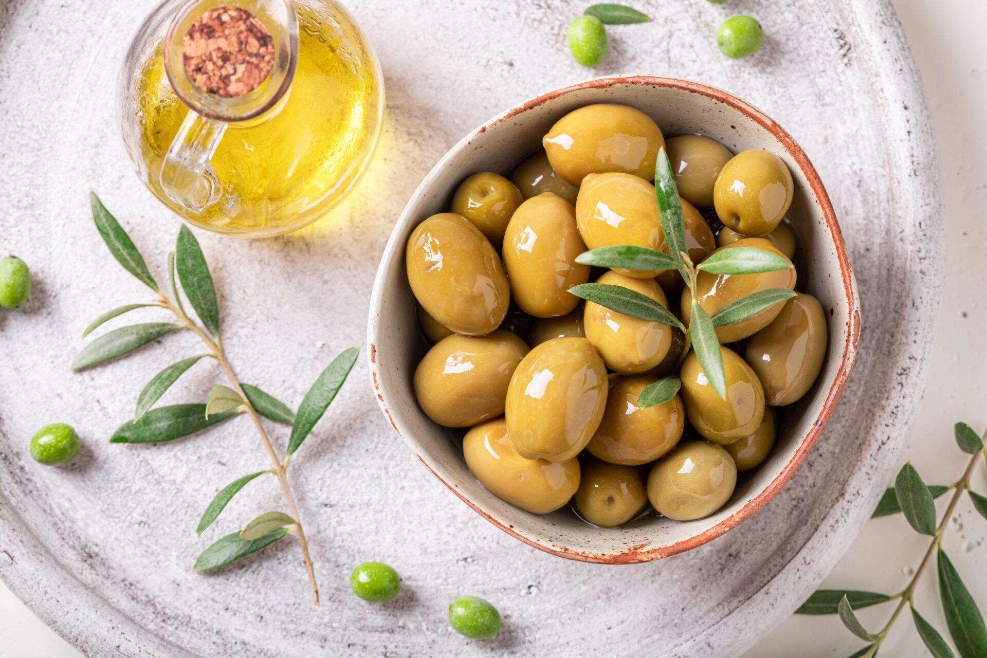 Olive oil in a bottle and a bowl with olives.
