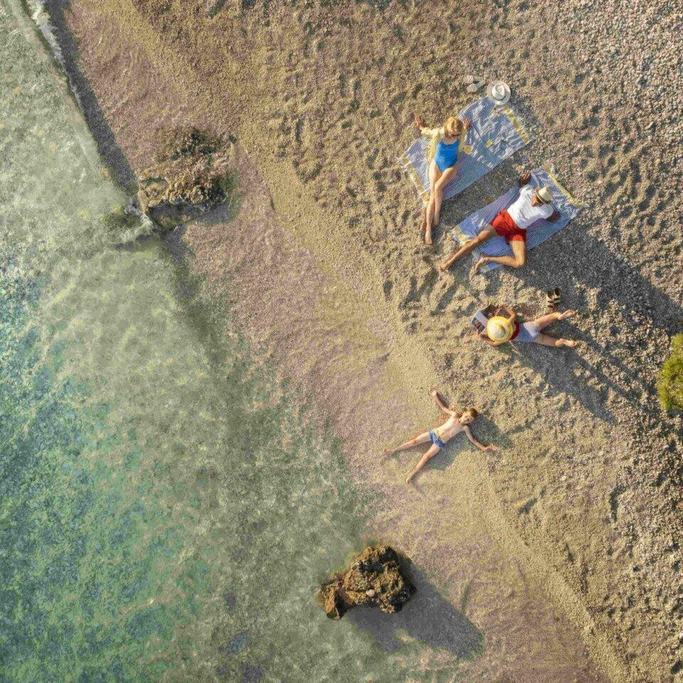 Aerial view of a family relaxing on a pebble beach in Croatia