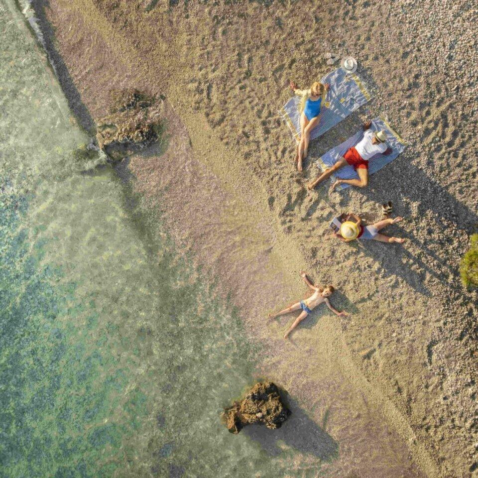 Aerial view of a family relaxing on a pebble beach in Croatia
