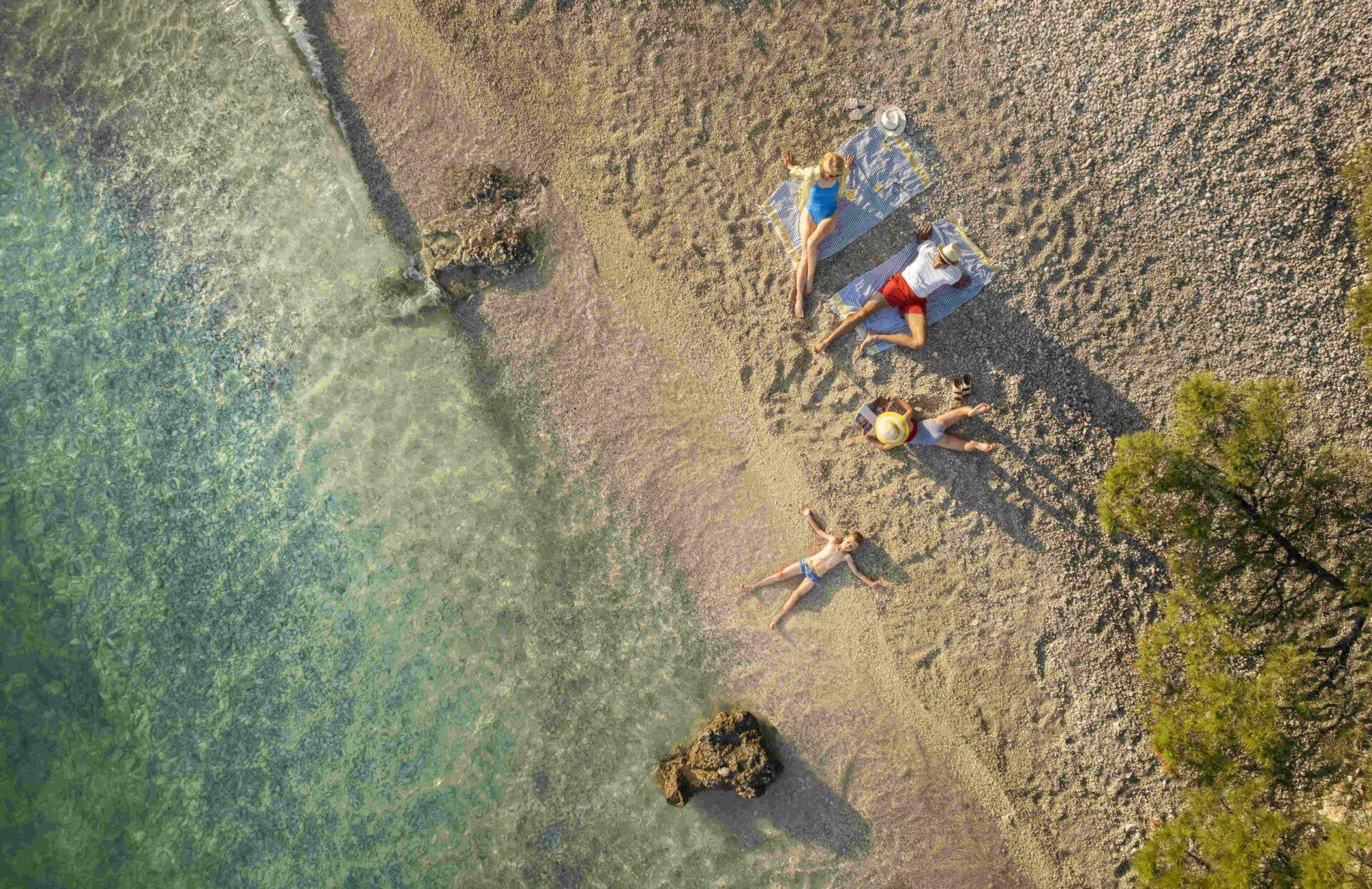 Aerial view of a family relaxing on a pebble beach in Croatia