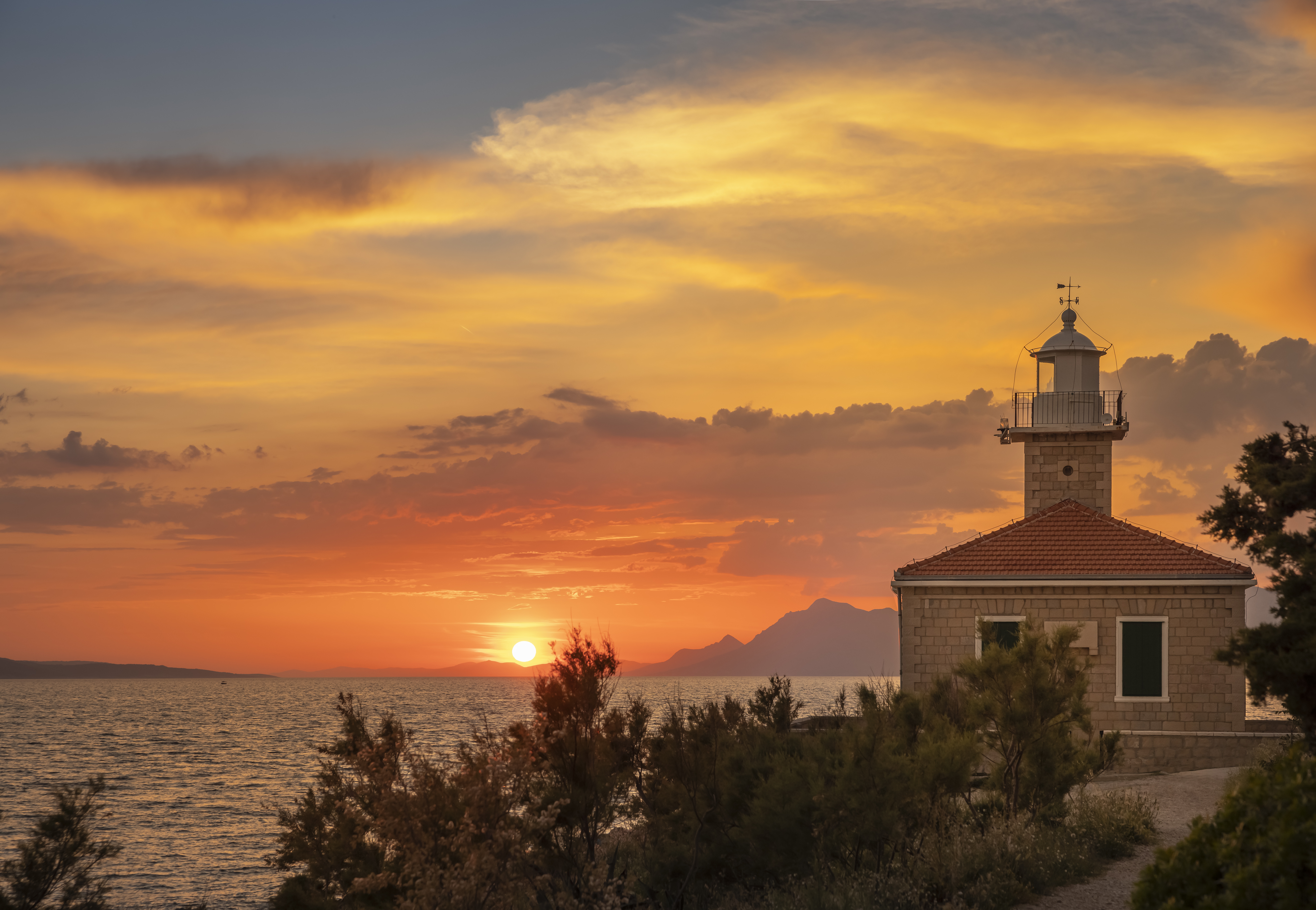 Blick auf den Sonnenuntergang mit Leuchtturm an der Makarska Riviera