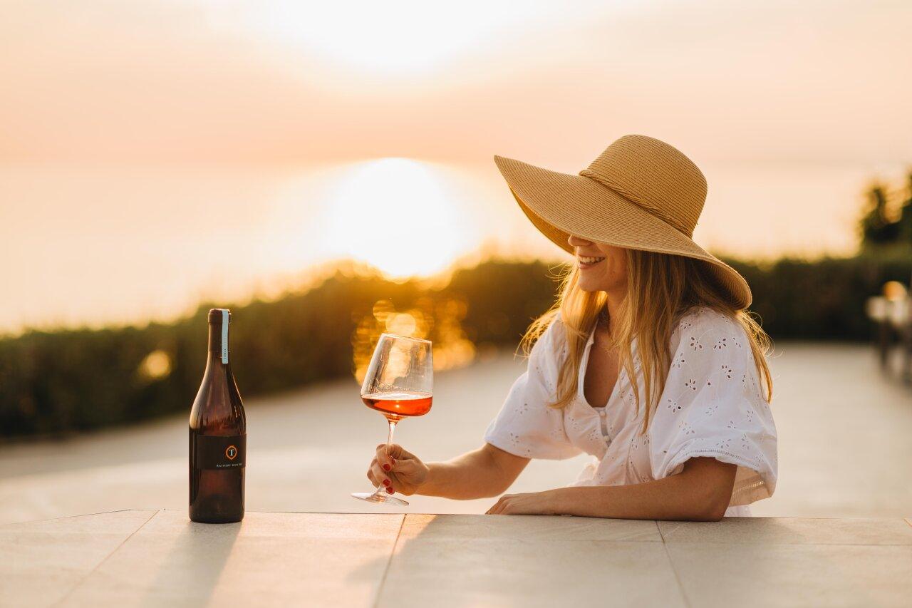 Eine Frau genie&szlig;t ein Glas Wein beim Sonnenuntergang in Poreč