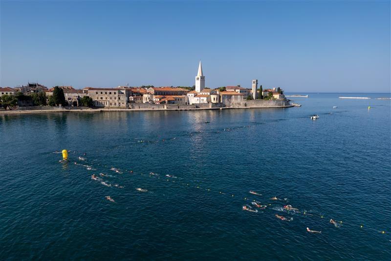 Swimmers take part in the Poreč Dolphin swimming event, making their way to Poreč Old Town