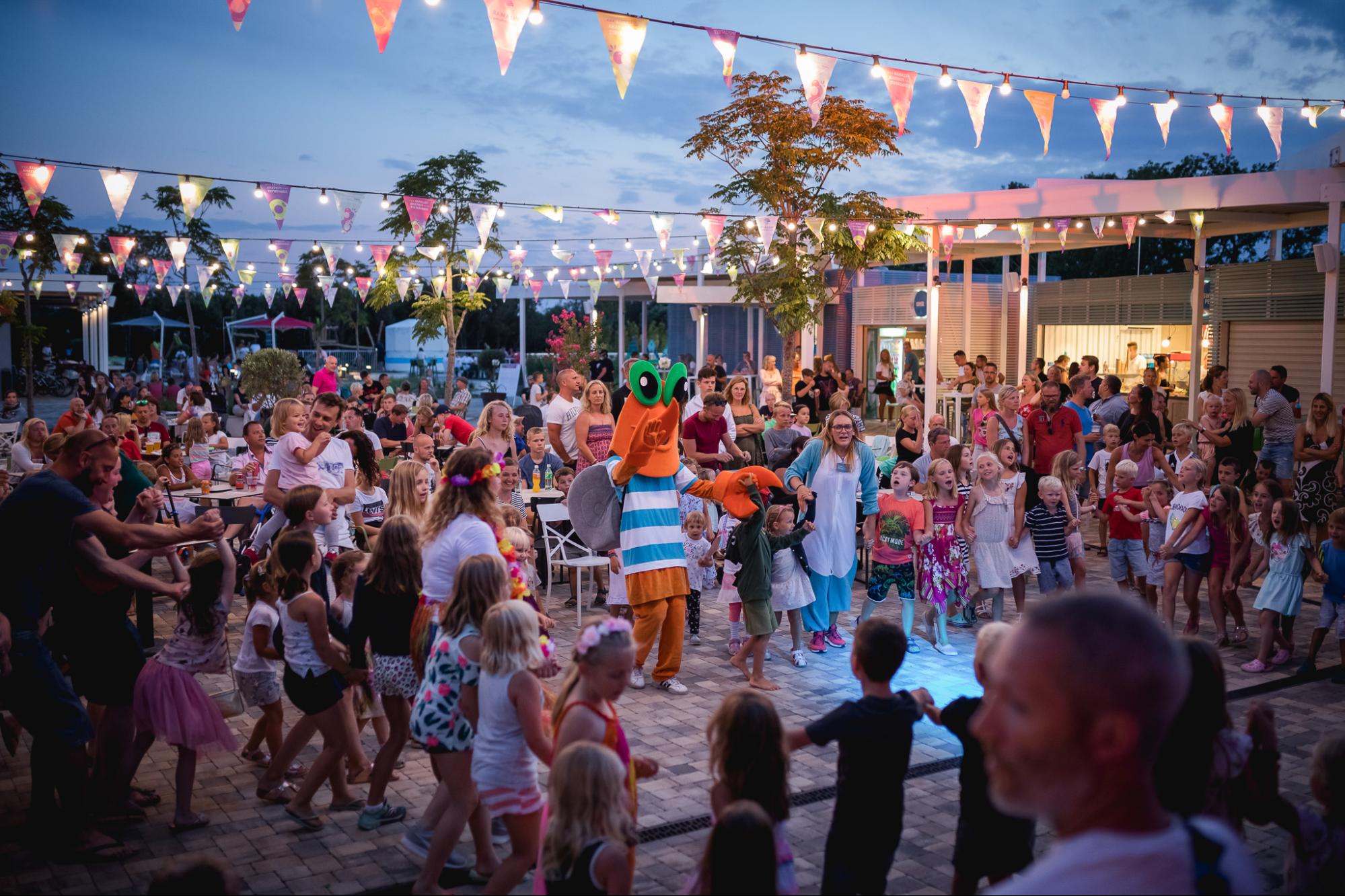 Crowd enjoying a family-friendly evening event with music and the Maro mascot at Funtana Summerfest