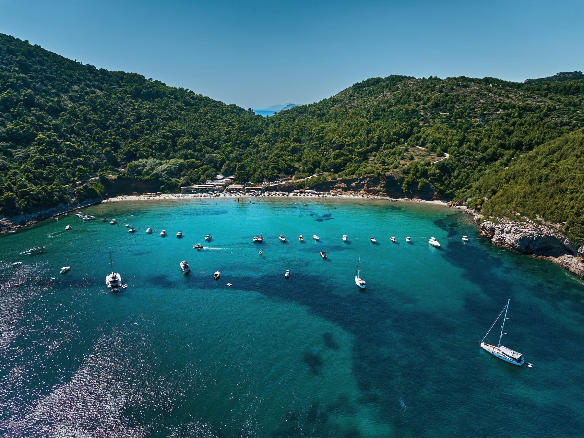 Plaža &Scaron;unj iz zraka na otoku Lopudu s usidrenim brodovima i zelenim brežuljcima
