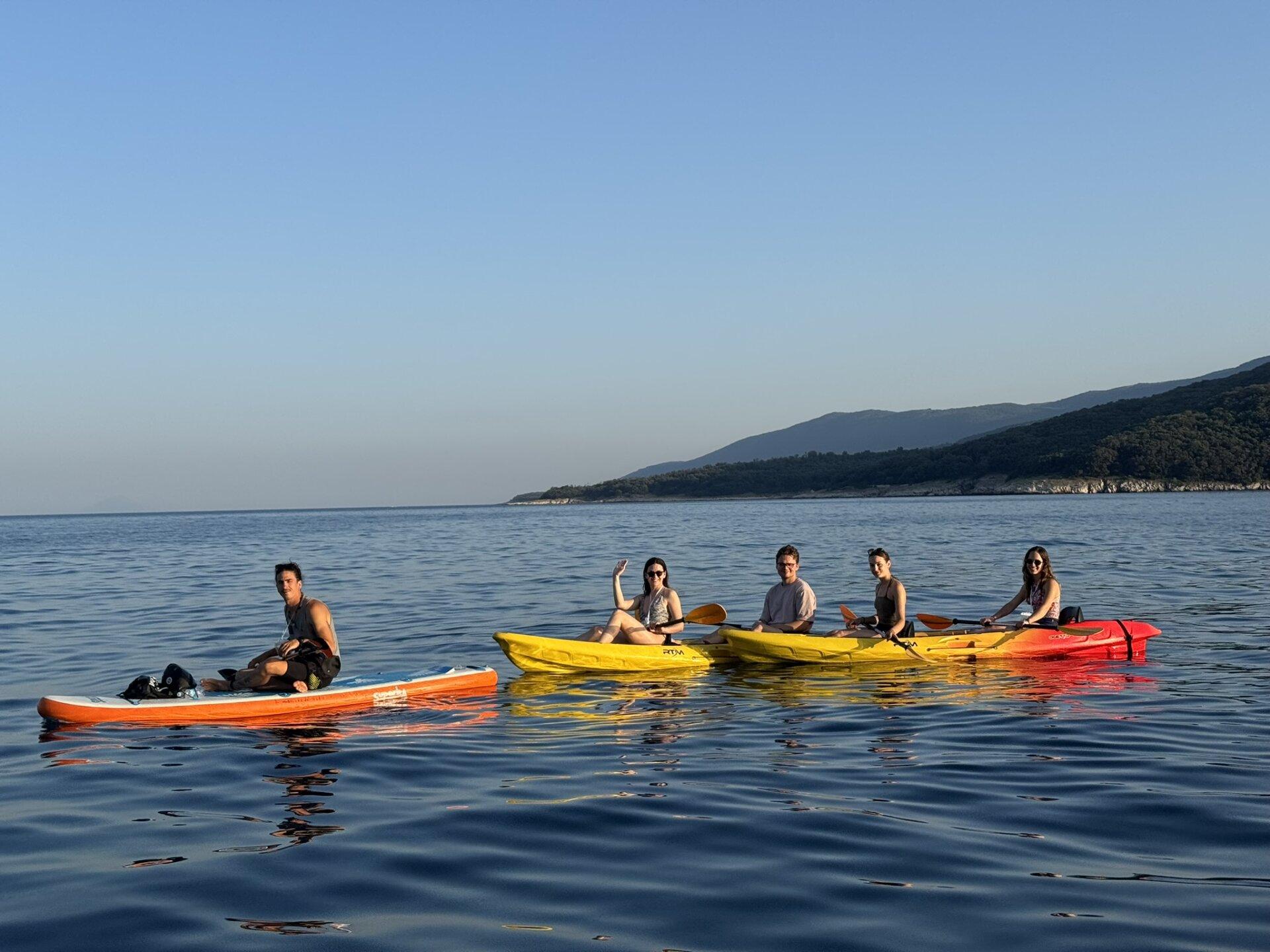 Eine Gruppe Kajakfahrer mit ihrem Guide auf einem Paddelbrett genießen die ruhige See auf einer Kajaktour in der Bucht von Rabac