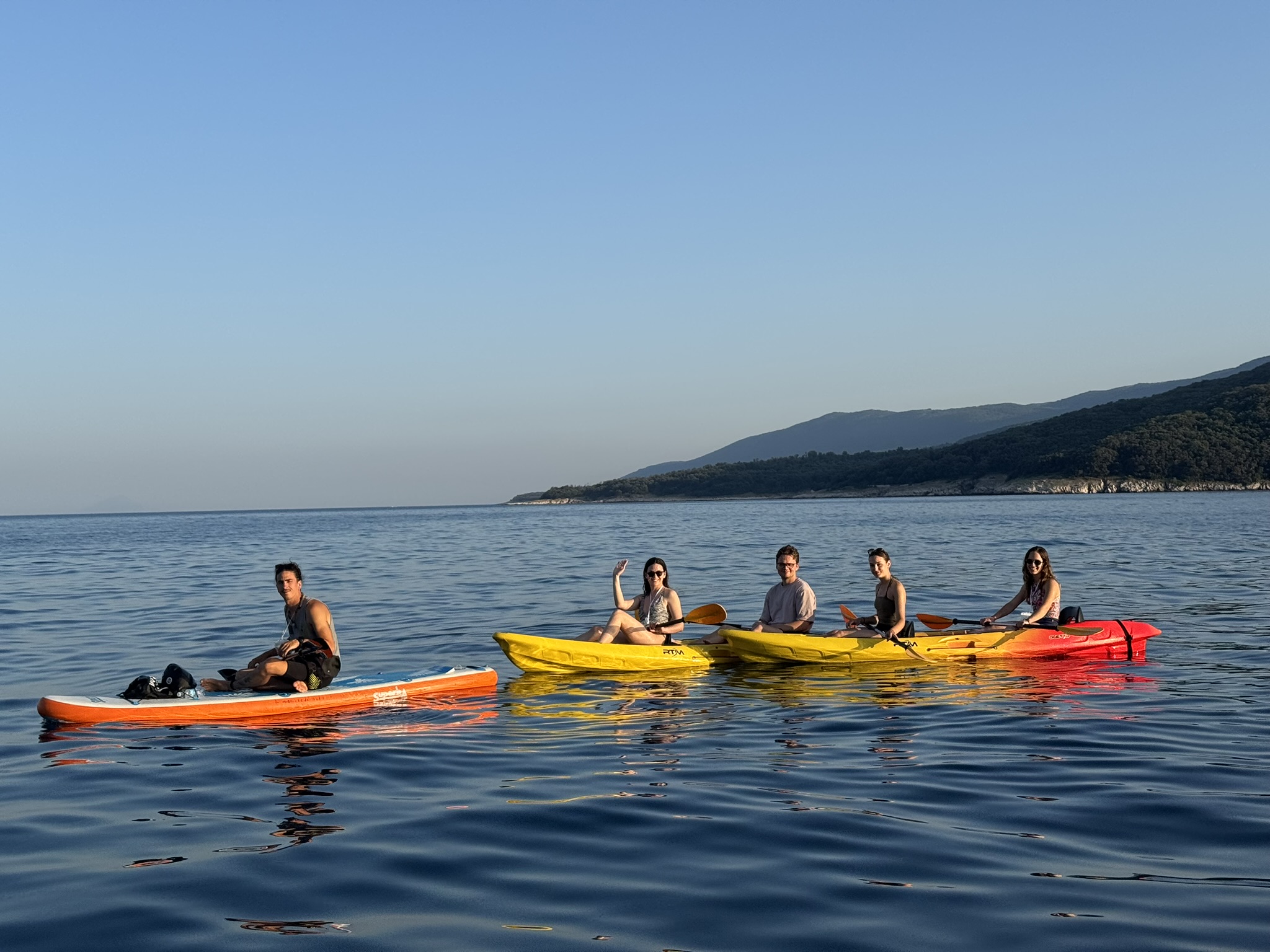 Grupa kajaka&scaron;a i vodič na SUP dasci uživaju na mirnom moru tijekom kajaka&scaron;ke ture u uvali Rabac. 