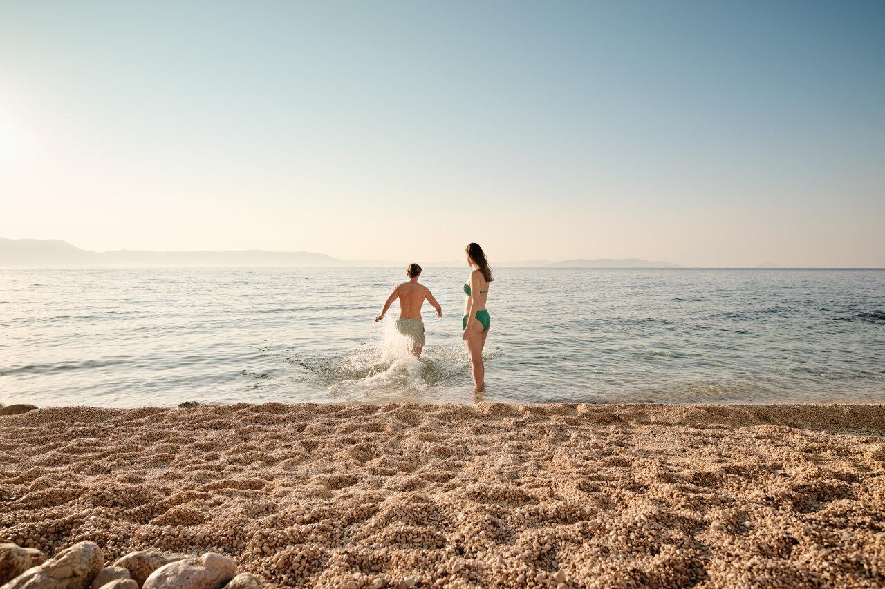Ein Paar an einem Kiesstrand in Rabac geht ins Meer