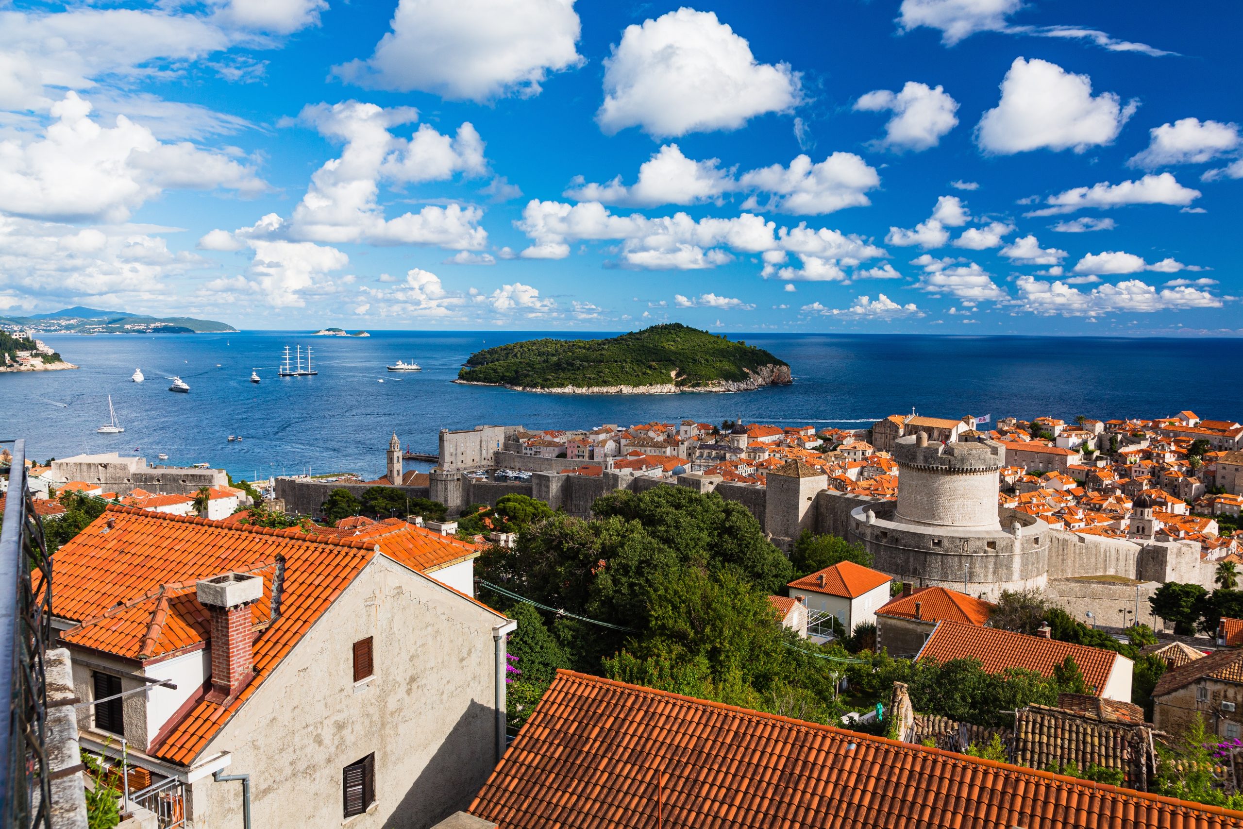 View of Lokrum Island from Dubrovnik’s Old Town, with terracotta rooftops, medieval city walls, and the Adriatic Sea in the background.