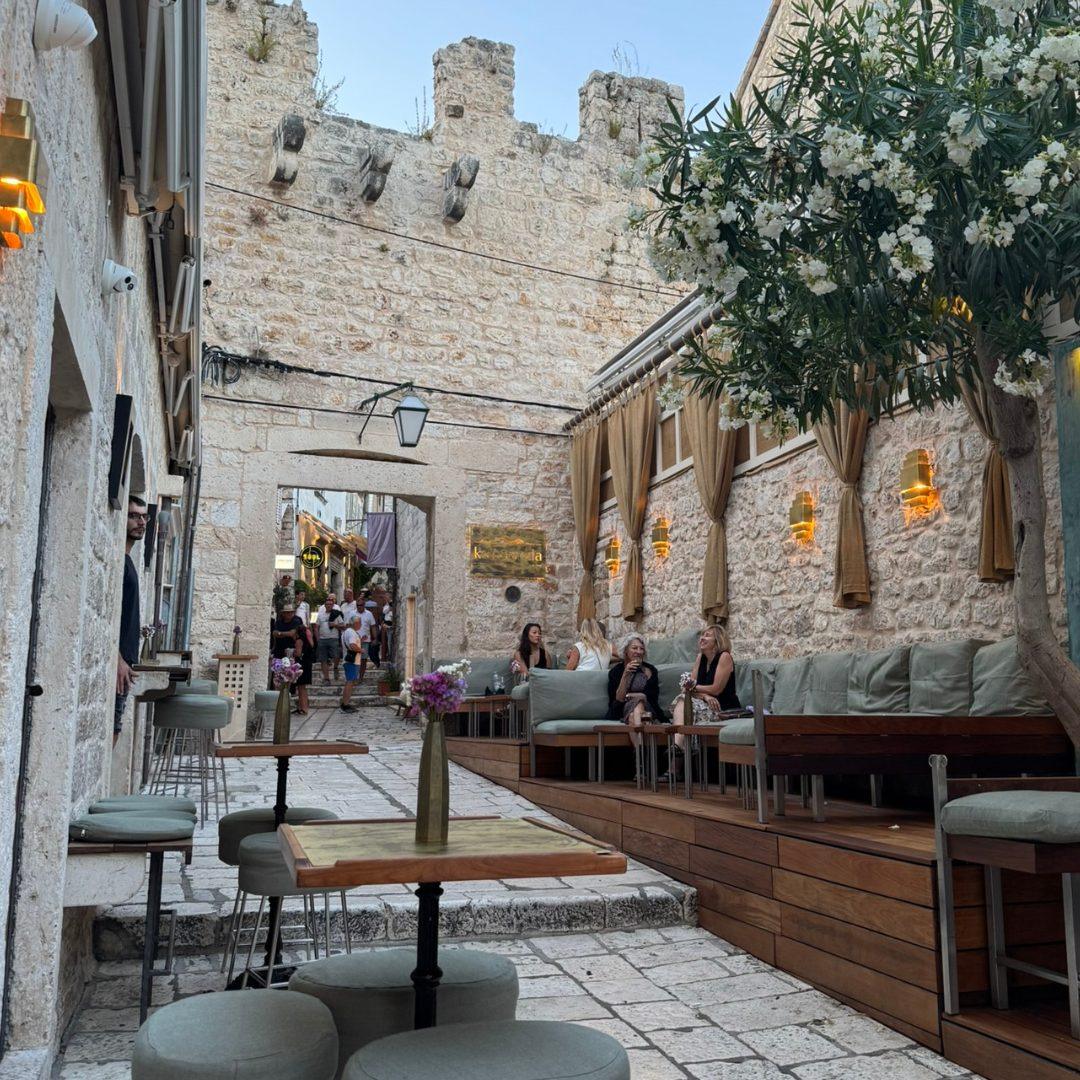 Outdoor lounge seating along Hvar’s old stone streets with cosy sofas, tables, and historic walls in the background.