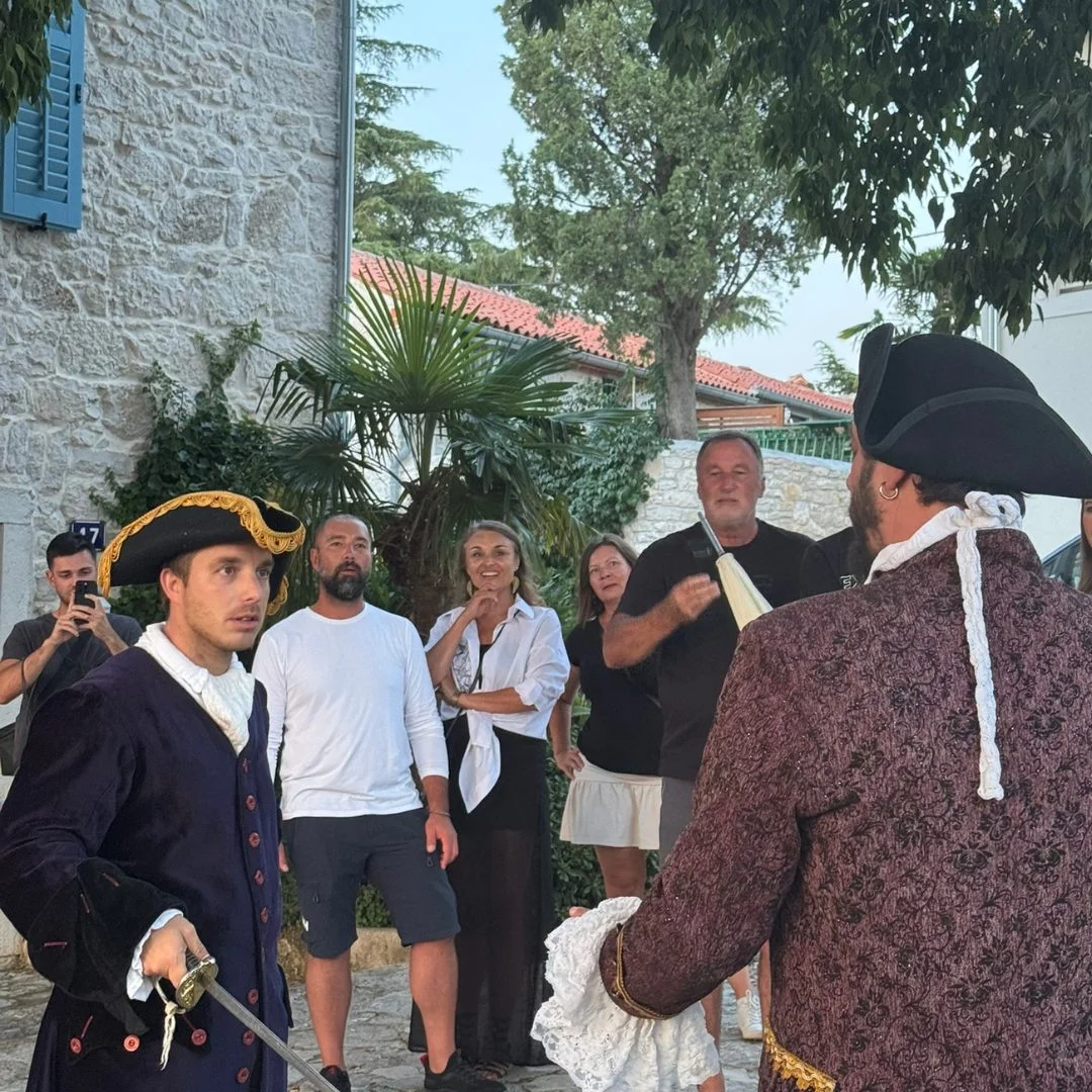 Darsteller in Kost&uuml;men aus dem 18. Jahrhundert spielen eine Duellszene w&auml;hrend der Casanova-Tour in Vrsar, w&auml;hrend das Publikum aufmerksam zusieht.