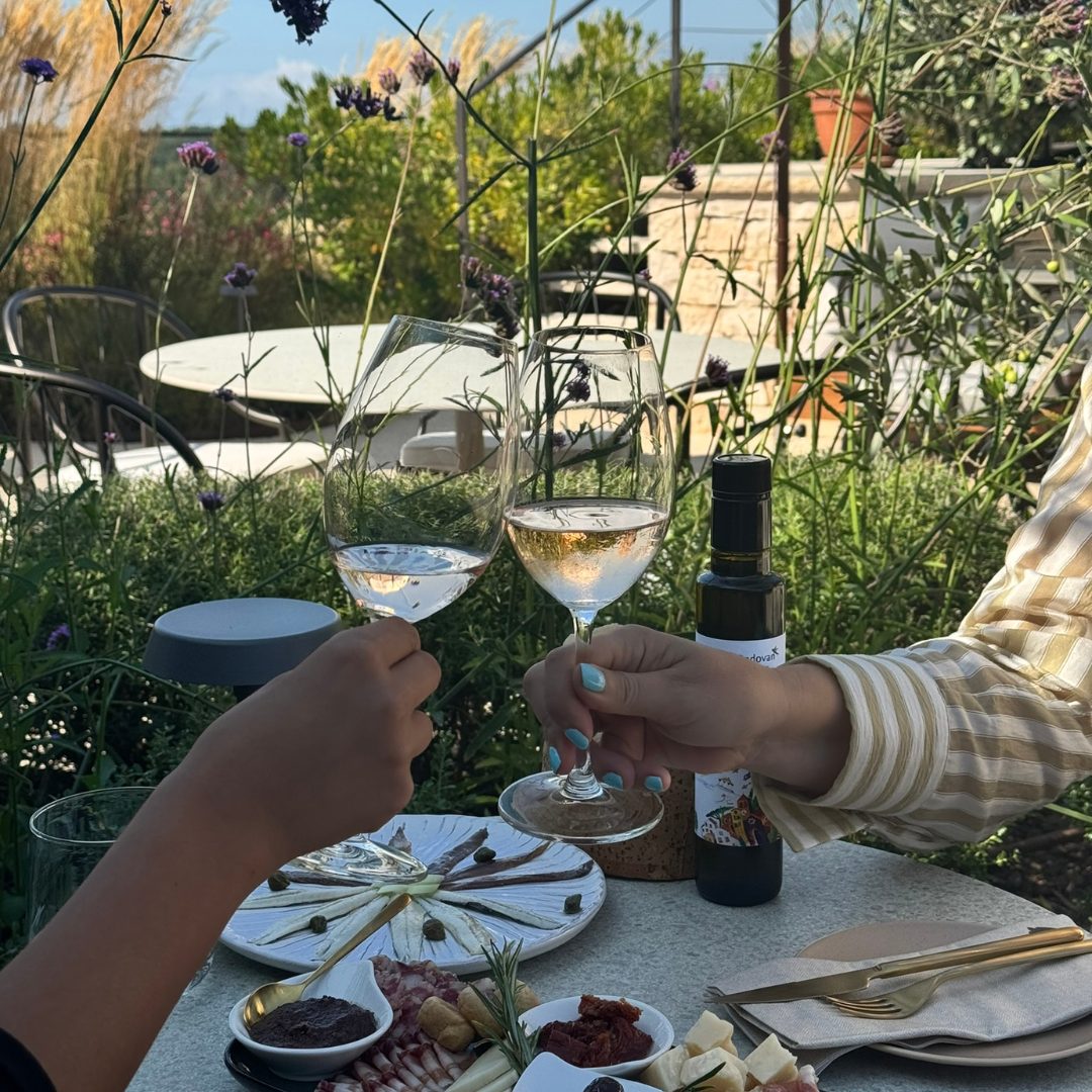 Toasting with glasses of wine over a table set with Istrian delicacies at Radovan Wines terrace.