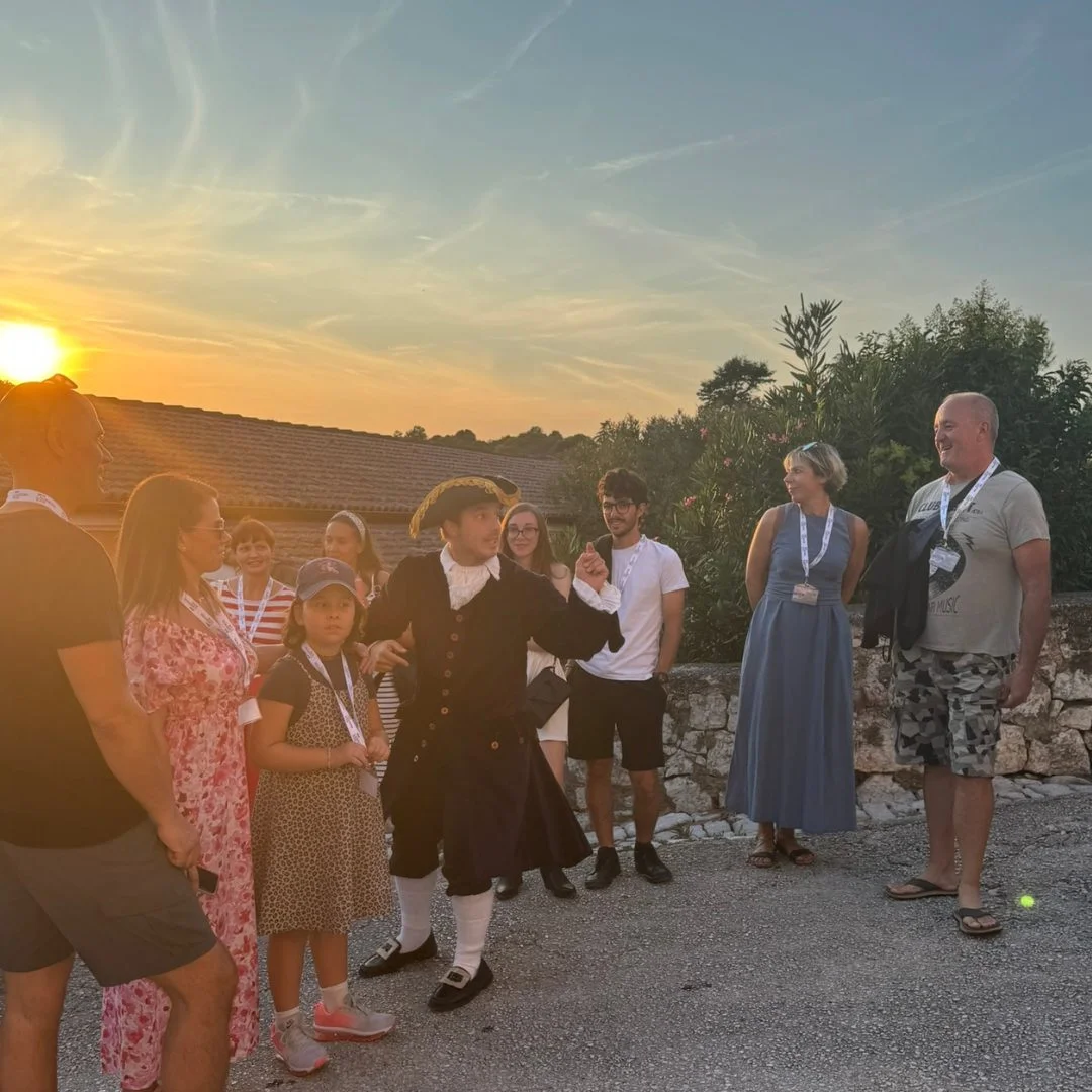 Ein Darsteller, der Don Gerolamo spielt, f&uuml;hrt die Besuchergruppe bei Sonnenuntergang durch die Stra&szlig;en von Vrsar. 