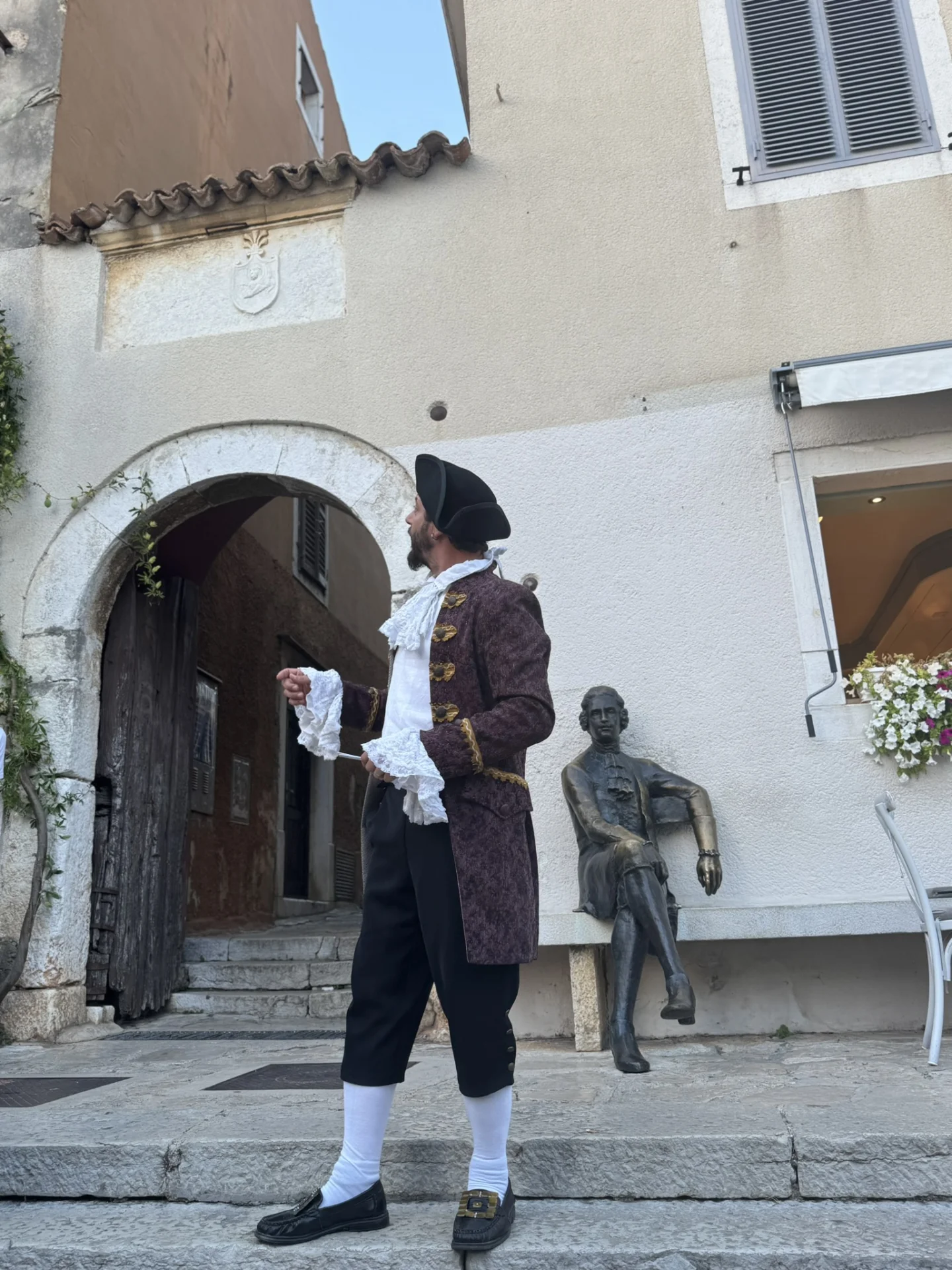 Ein Darsteller in seinem Kost&uuml;m aus dem 18. Jahrhundert tritt am alten Stadttor in Vrsar auf, nahe der Bronzestatue von Casanova. 