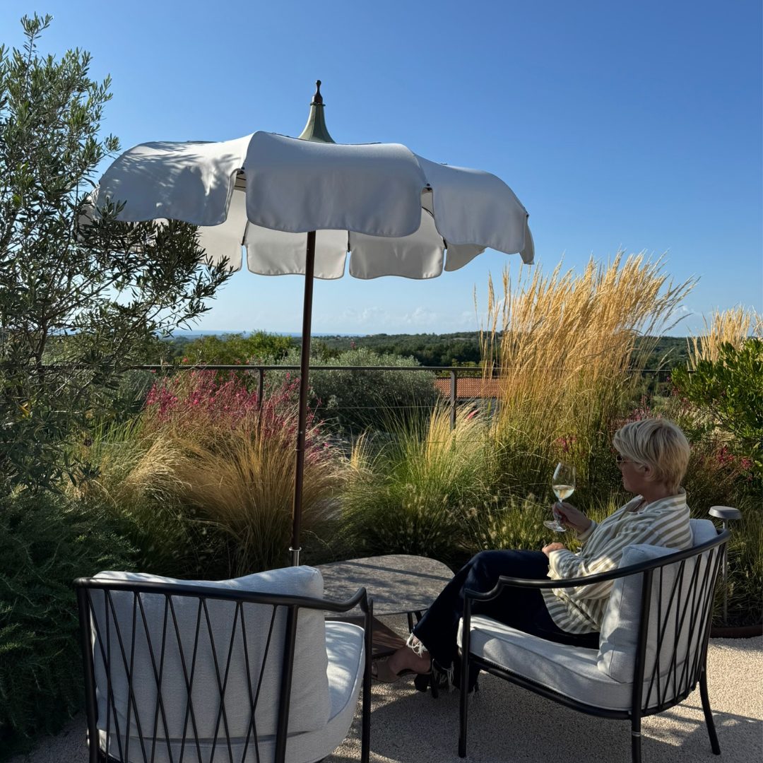 Guest relaxing with a glass of wine under a white umbrella at Radovan Wines terrace.