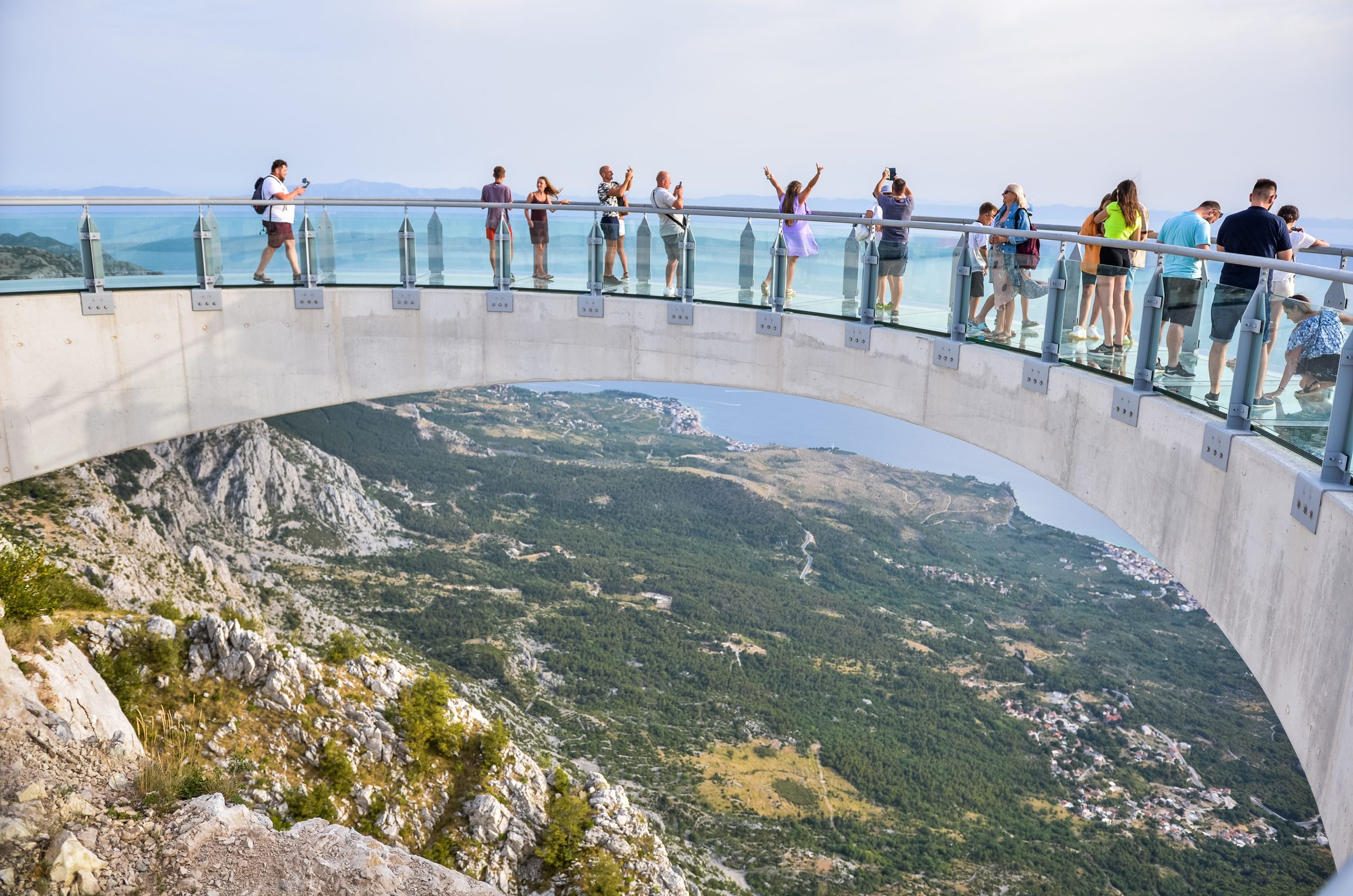 People enjoying the Biokovo Skywalk glass platform with panoramic views over Makarska and the Adriatic coast.