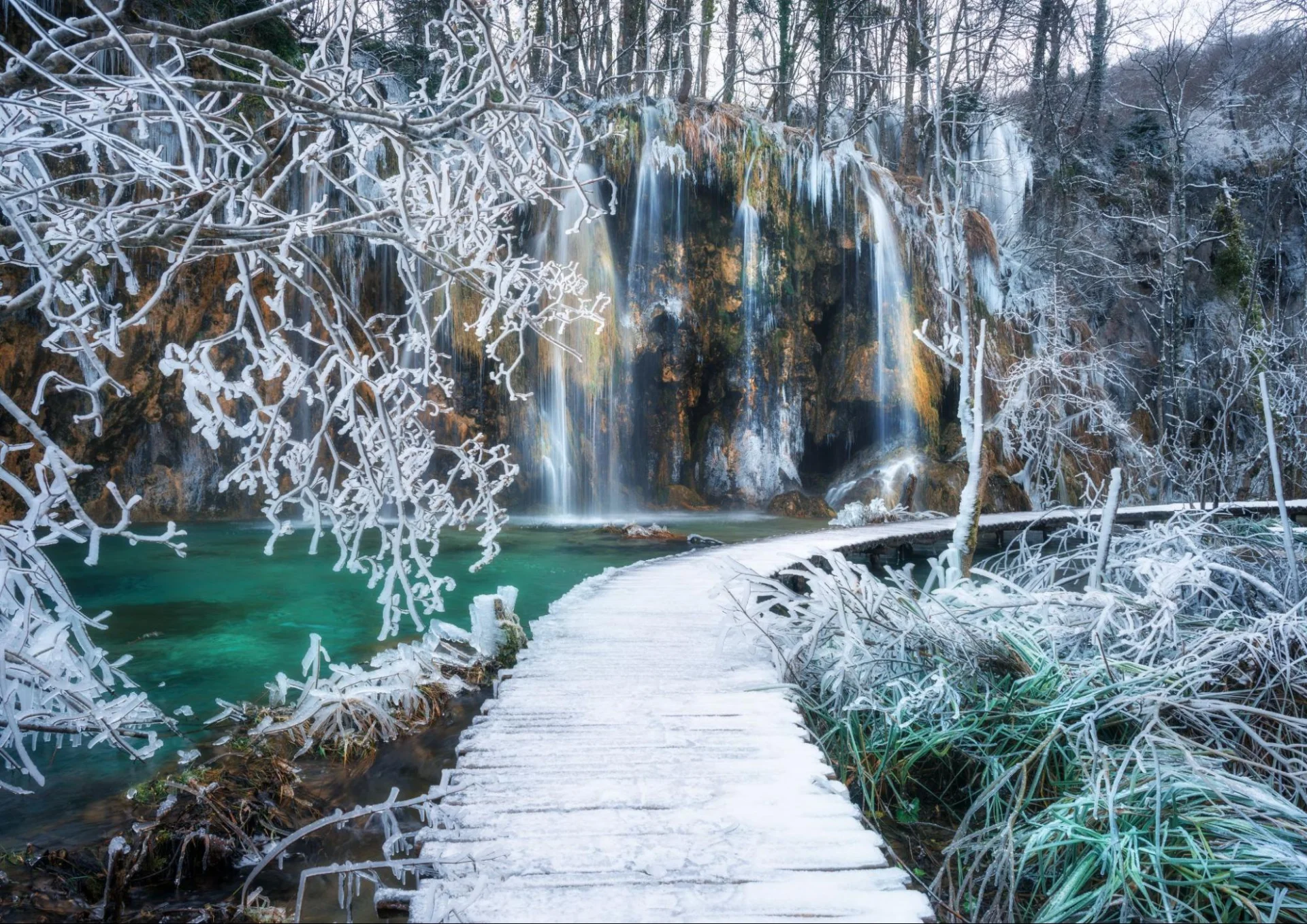 Nacionalni park Plitvička jezera zimi, sa zaleđenim slapovima i snijegom prekrivenim stazama.