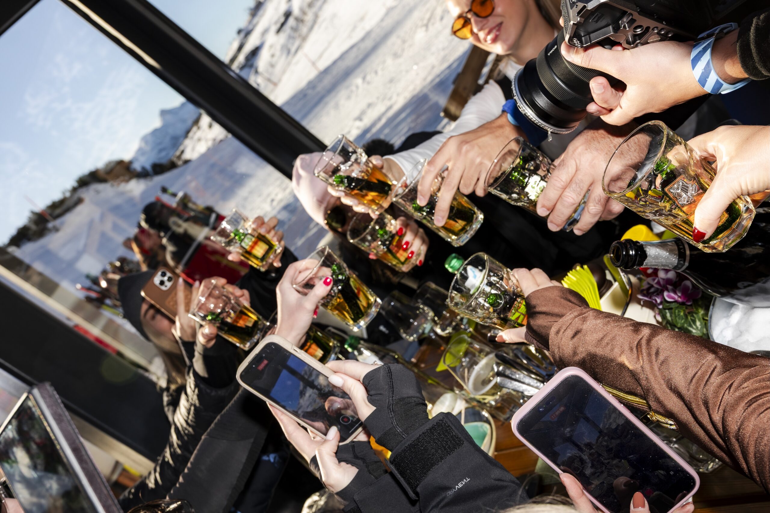 Group of guests raising glasses during an apr&egrave;s-ski gathering in Obertauern, with snow-covered slopes in the background