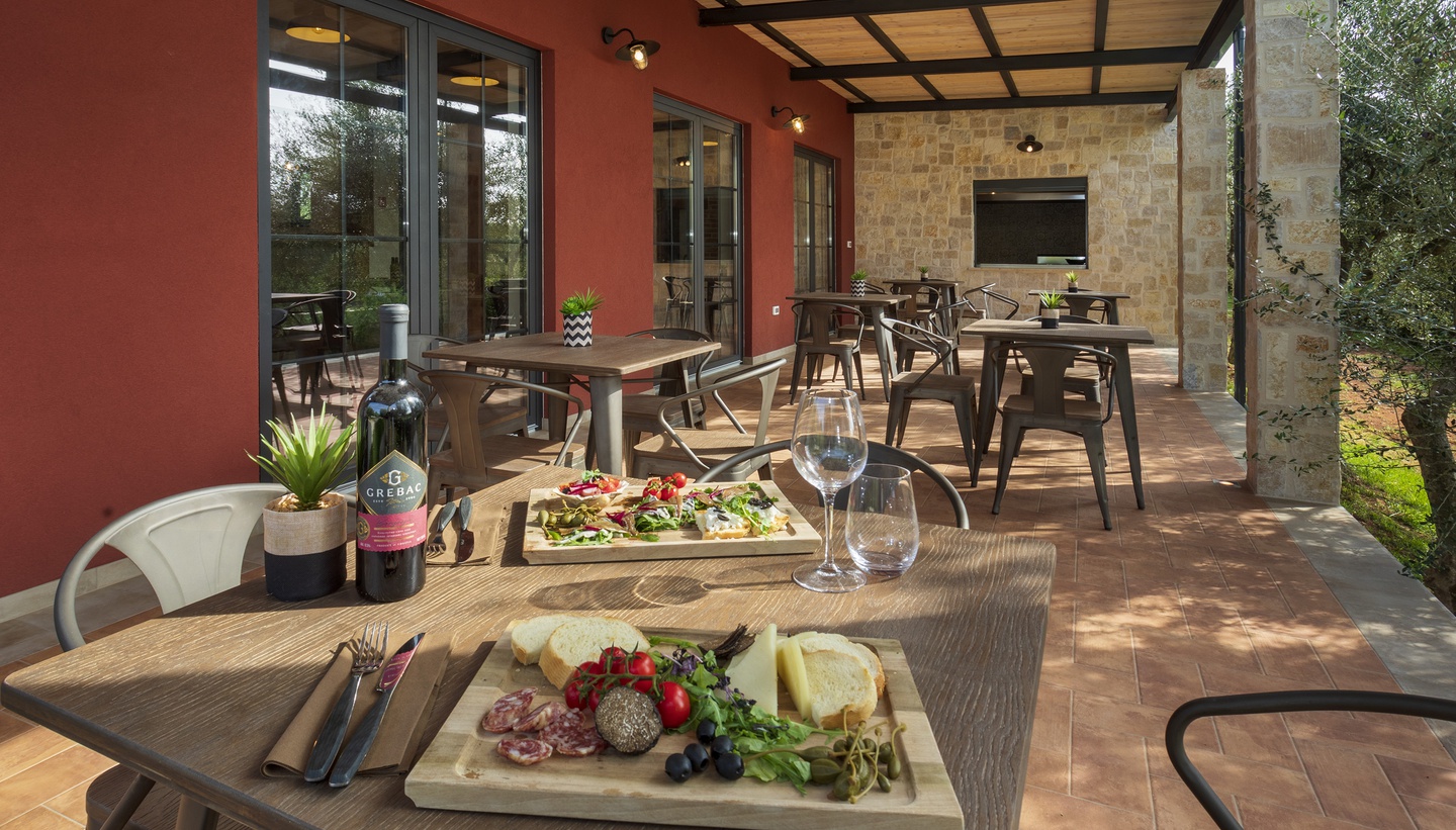 Outdoor terrace dining with olive oil, bread, cheese, and local delicacies on the table.