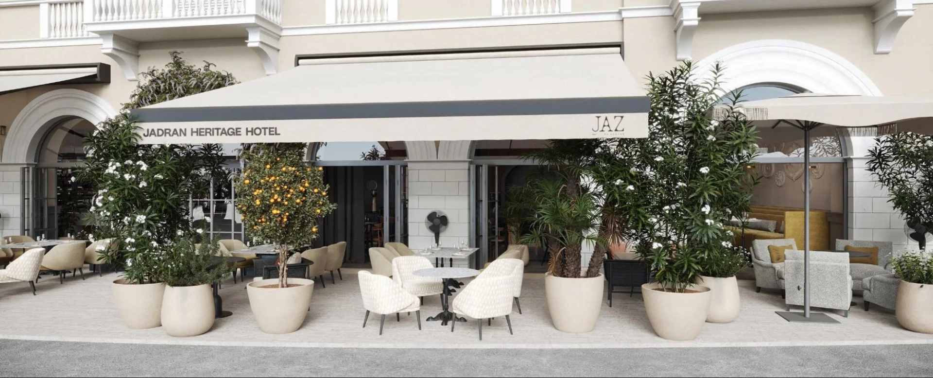 Elegante Hotelaufnahme und eine stilvolle Terrasse im Erdgeschoss, geschm&uuml;ckt mit &uuml;ppigen Topfpflanzen und Sitzgelegenheiten im Freien im JAZ by Ana Ro&scaron;.