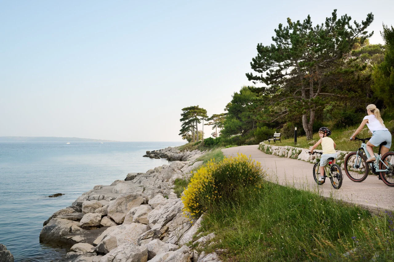 Mutter und Kind fahren auf einem malerischen K&uuml;stenweg auf der Insel Rab mit der Adria neben sich