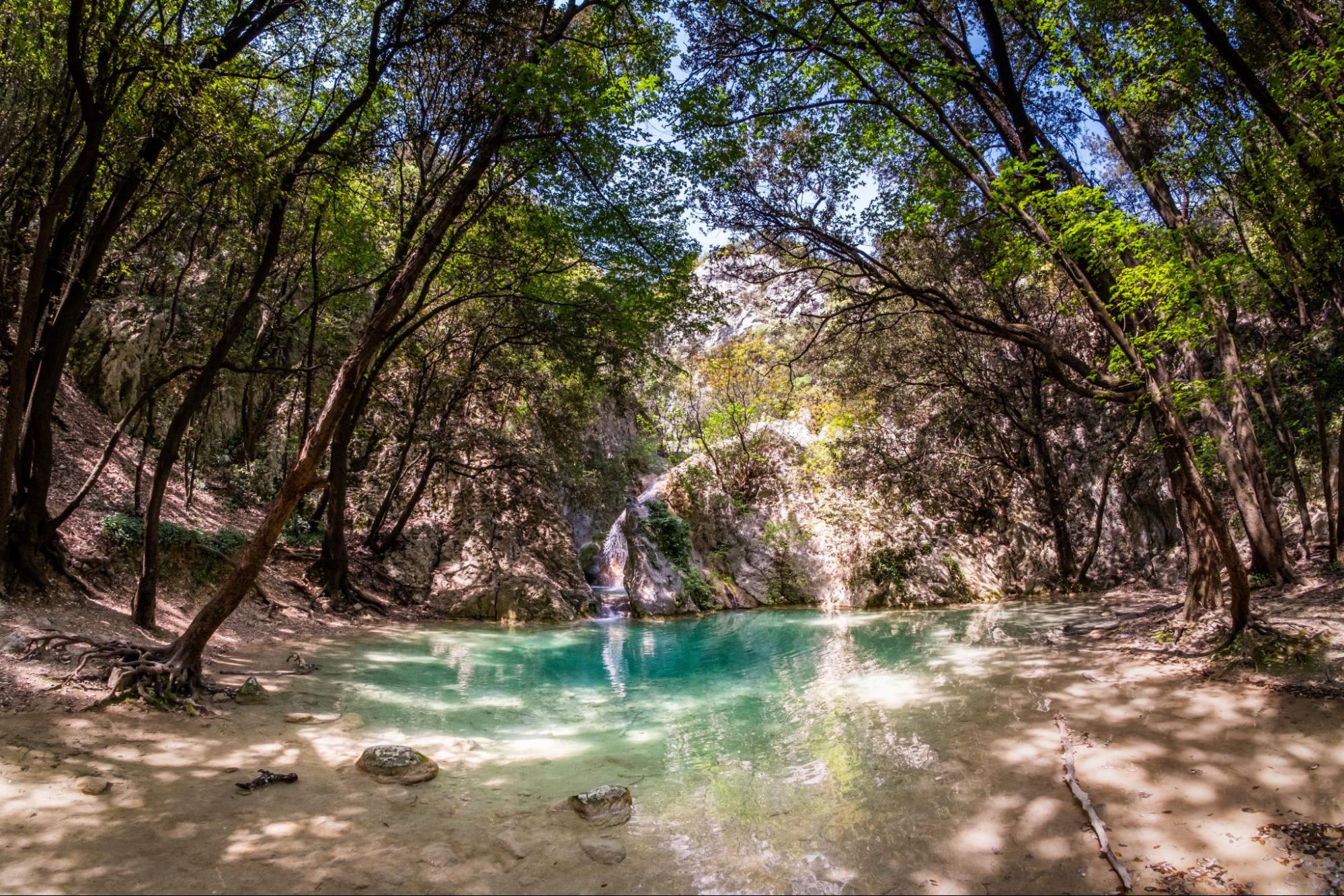 Shaded forest pool with a small waterfall and turquoise water along a nature trail near Labin.