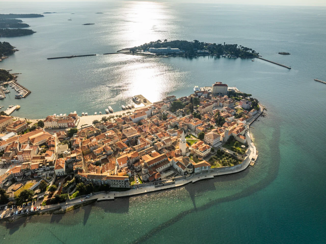 Luftansicht von der historischen Altstadt von Poreč auf einer kleinen Halbinsel, mit Terracotta-D&auml;chern, umgeben vom klaren blauen Wasser der Adria und eine nahe gelegene Insel im Hintergrund
