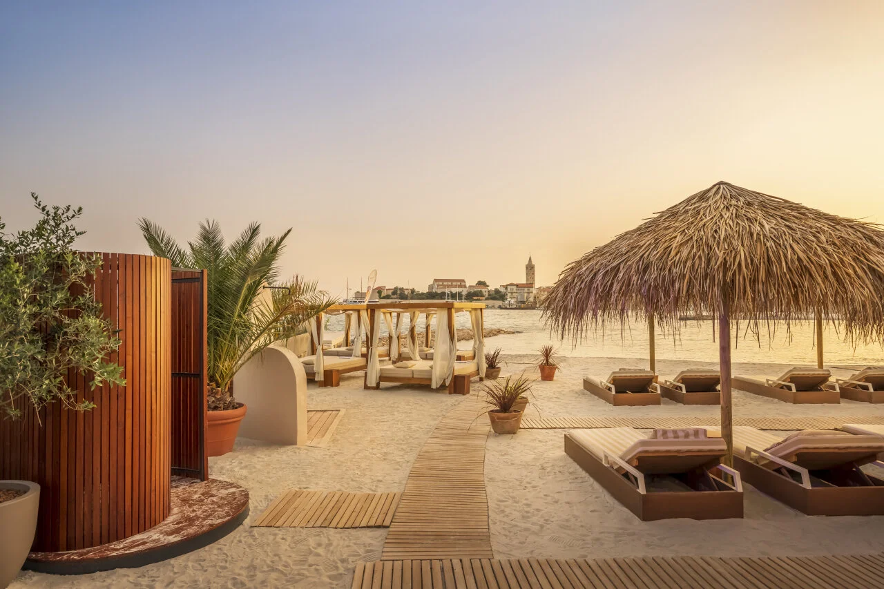 A perfect beach day on Rab - soft sand, calm water and rows of sun loungers under the Adriatic sun