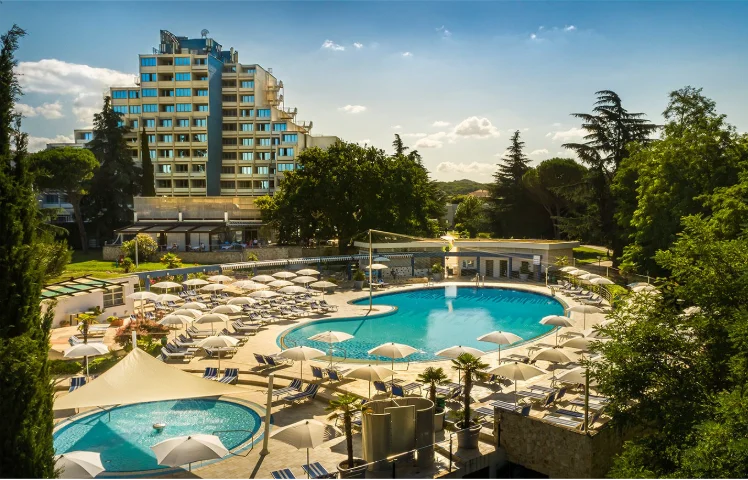Pogled na Valamar Diamant Hotel s bazenom i ležaljkama.  