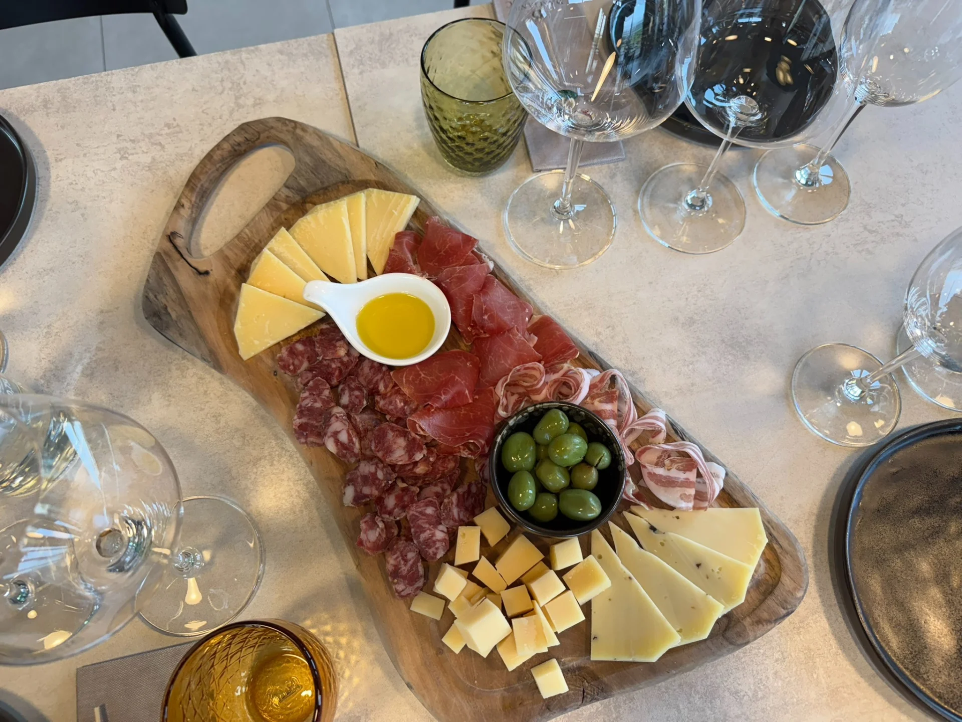 Drveni pladanj s istarskim sirevima, pr&scaron;utom, salamama, maslinama i maslinovim uljem posluženima uz ča&scaron;e za vino tijekom degustacije.
