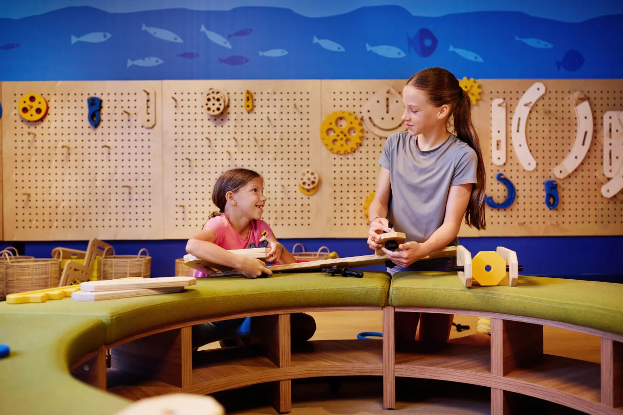 Two children taking part in a creative workshop and assembling wooden toys in the kids’ club at Arba Resort on Rab.