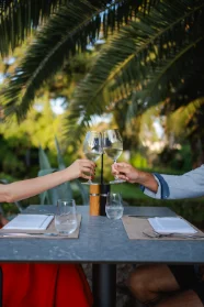 Two glasses of white wine raised over a restaurant table on Rab