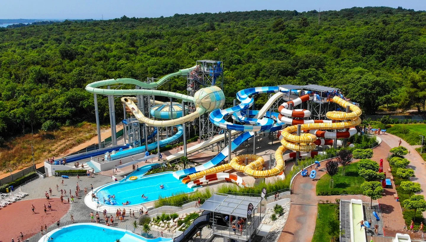 Aerial view of a large water park in Istria with colourful twisting slides, pools, and families enjoying a sunny day.