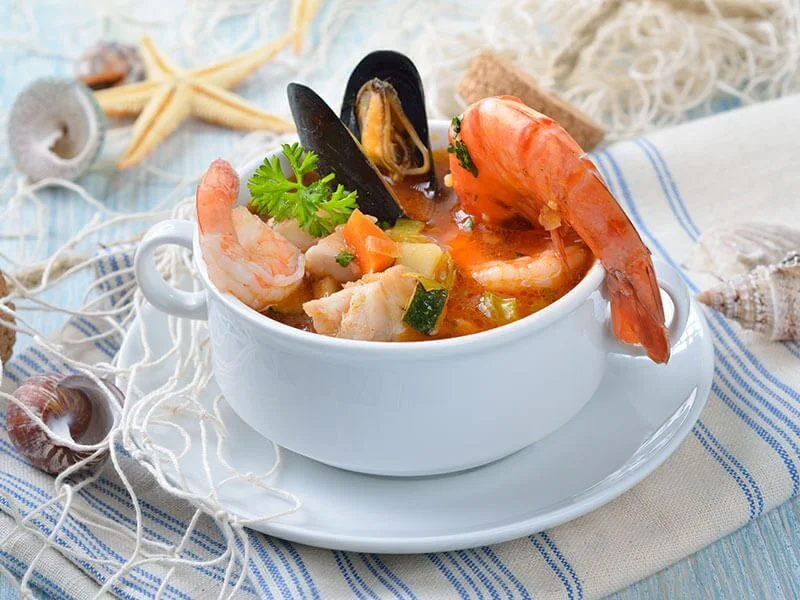 Elegantly plated seafood dish with prawns and shellfish in a rich sauce, styled with sea-inspired details
