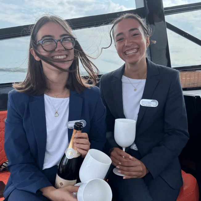 Members of the Experience Concierge team with a bottle of sparkling wine and glasses aboard the Colnago 45