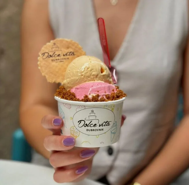 Two scoops of ice cream topped with crumbs and a decorative biscuit, served in a cup at Dolce Vita in Dubrovnik.