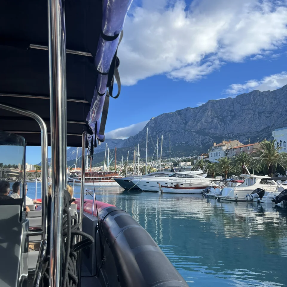 View from a speedboat in Makarska harbour with luxury yachts and Mount Biokovo in the background.