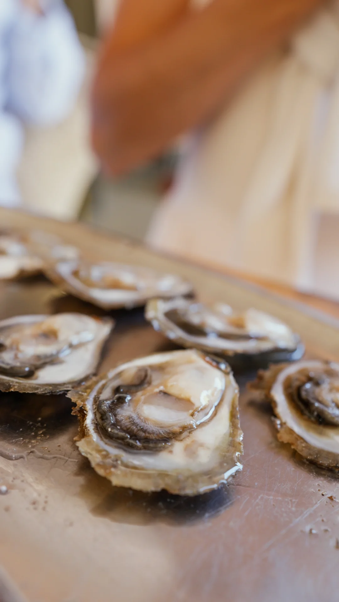 Details of fresh shellfish and oysters, from strings of shells by the sea to a full crate and preparation on a platter.