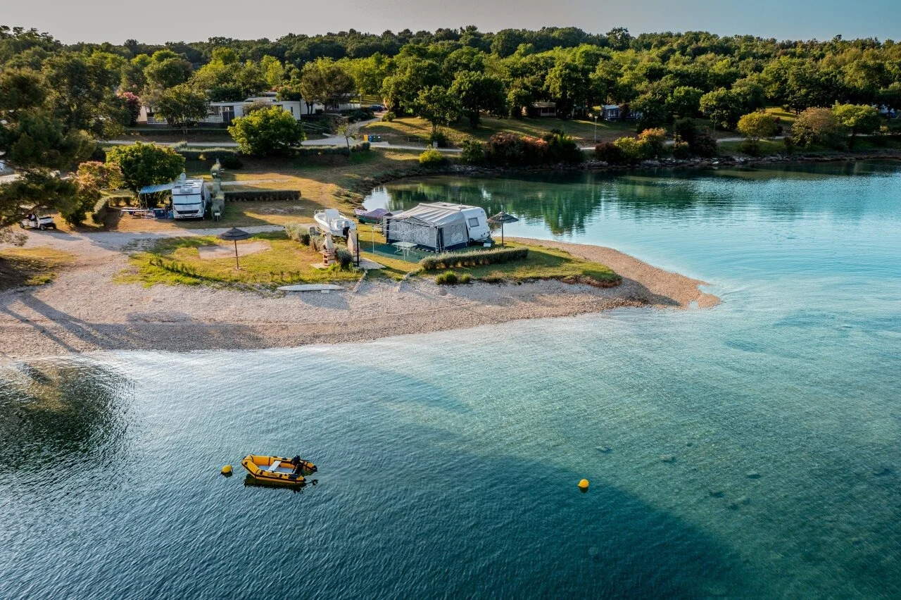 Pogled na sunčanu uvalu i kristalno more kampa Solaris, poznatog po naturističkim plažama i dubokom prirodnom hladu u Istri.