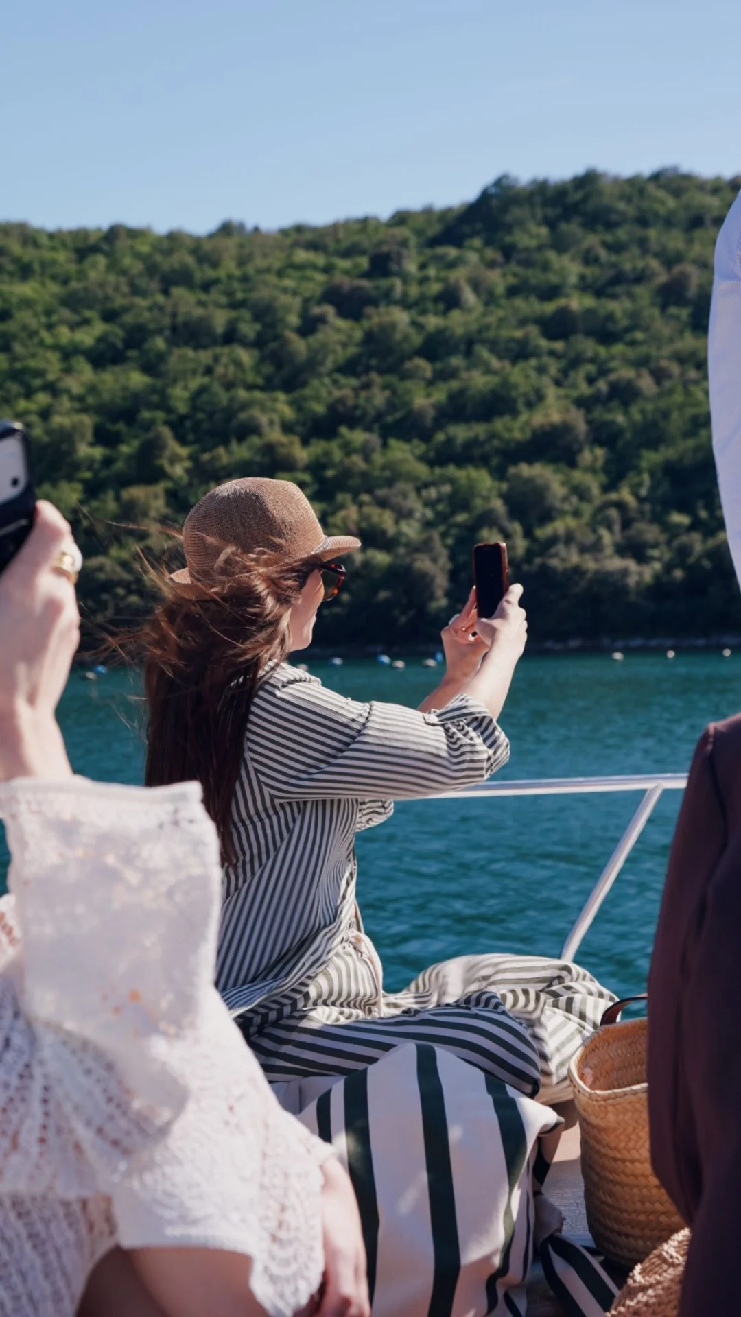 Tourists taking photos of the sea and green slopes of the Lim Channel with their phones.