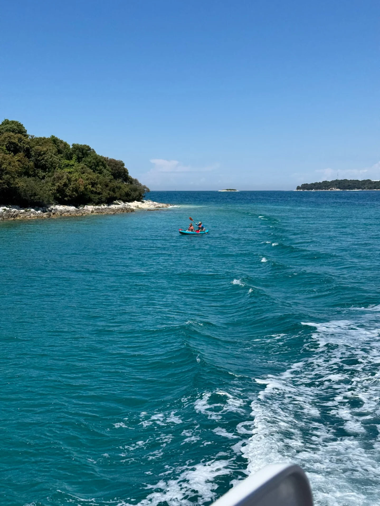 Turquoise sea, a kayak, and a rocky coastline during a cruise toward the Lim Bay.