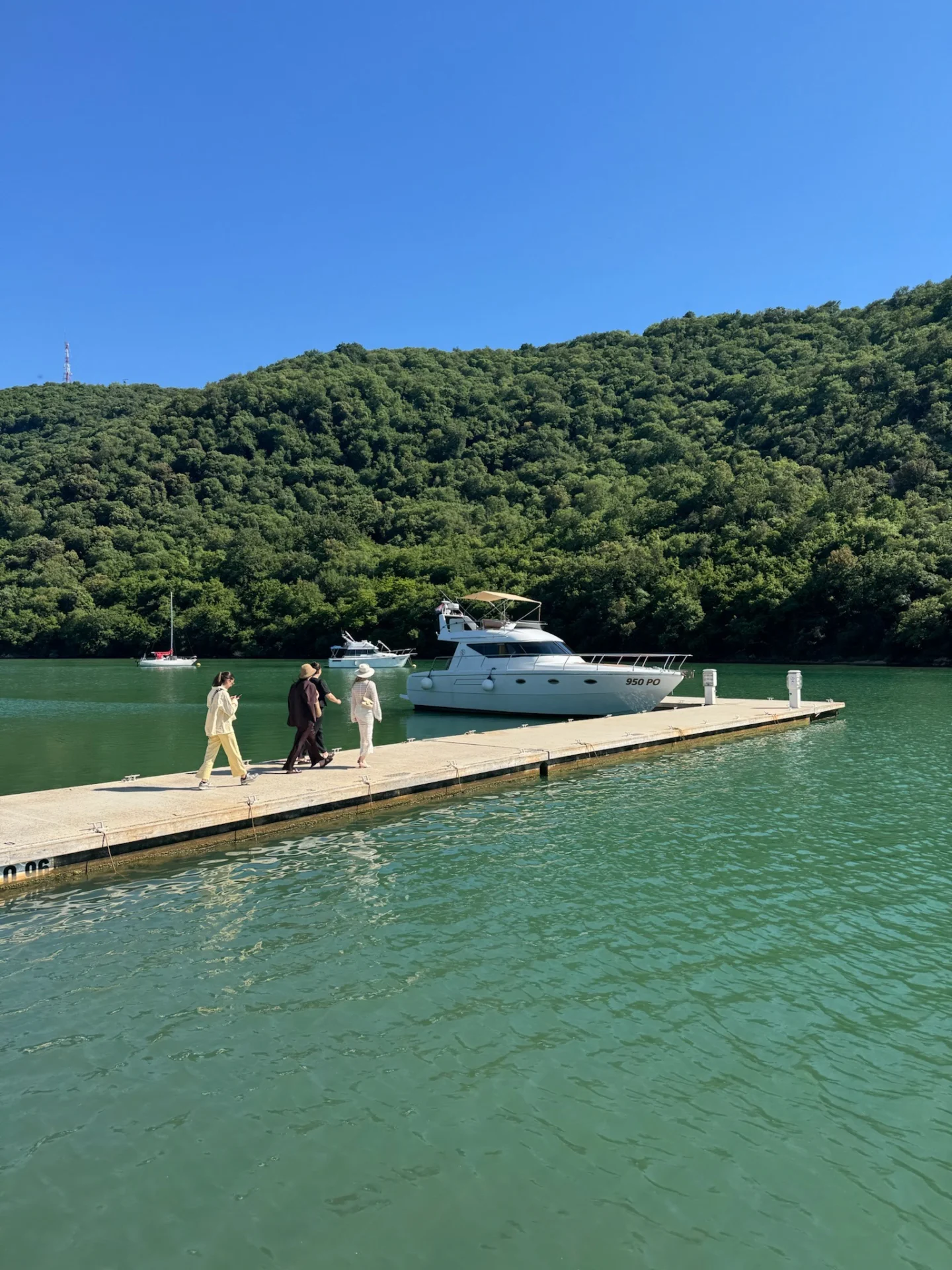 A boat moored in the Lim Bay surrounded by greenery and calm sea.