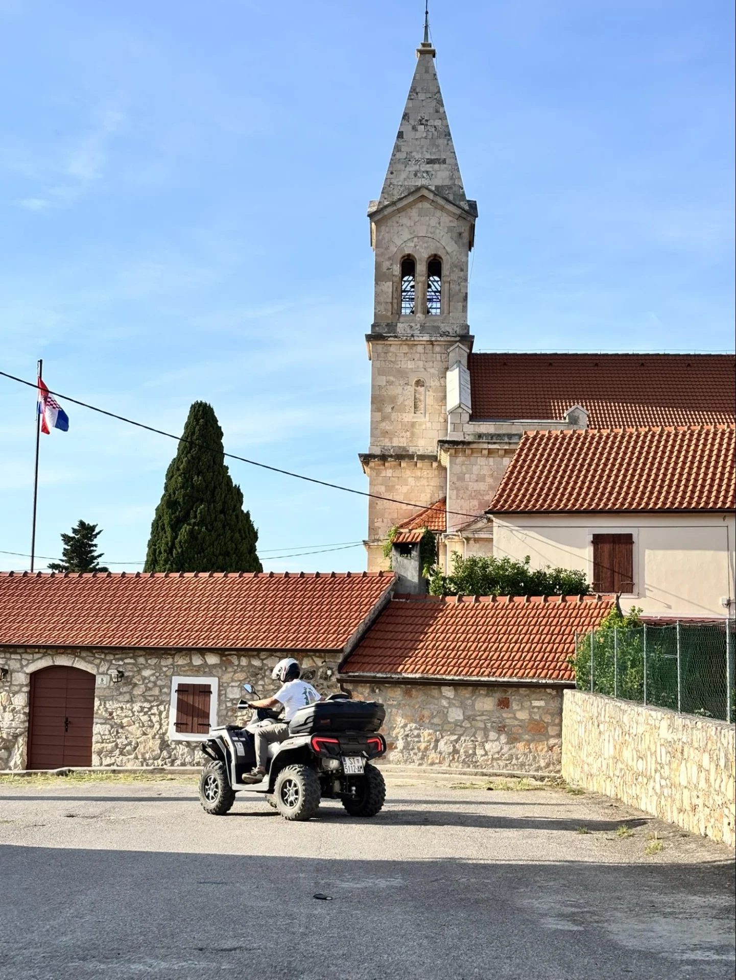 Vožnja quadom kroz malo naselje na otoku Hvaru pokraj tradicionalne kamene crkve.