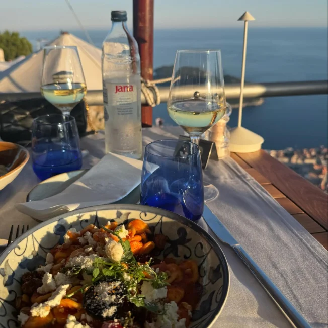 Served dish and glasses of wine at Panorama Restaurant on Mount Srđ overlooking Dubrovnik and the Adriatic Sea.